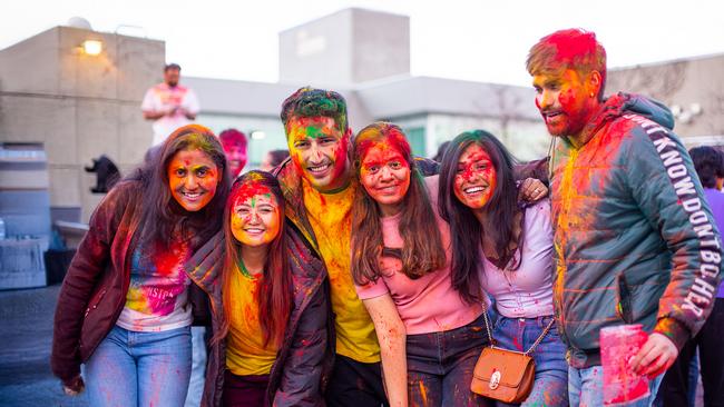 A group of happy people covered in rainbow-coloured powder