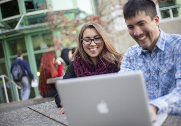 Two people looking at a laptop screen. 