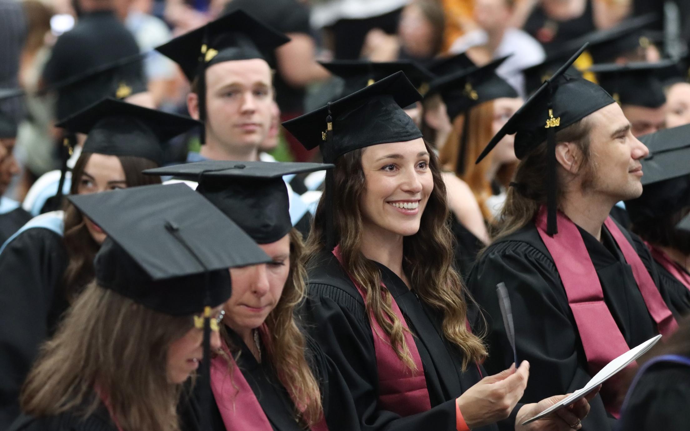 A group of graduates smile and listen to speeches