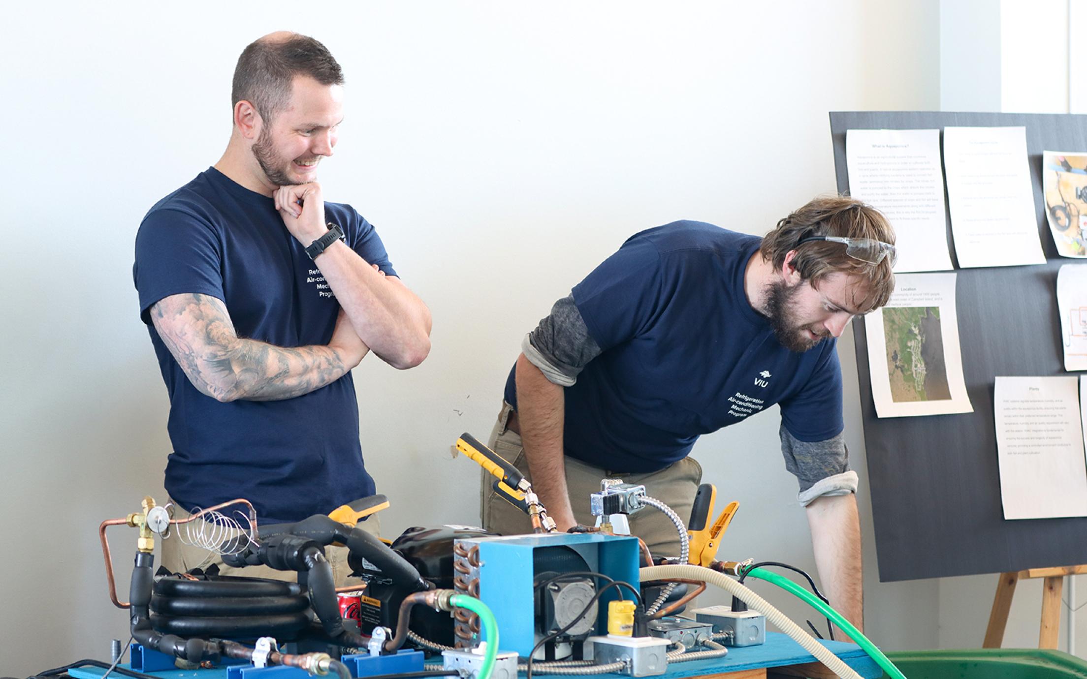 Two students showcase their Refrigeration and Air Conditioning Mechanic work for the food sovereignty project.