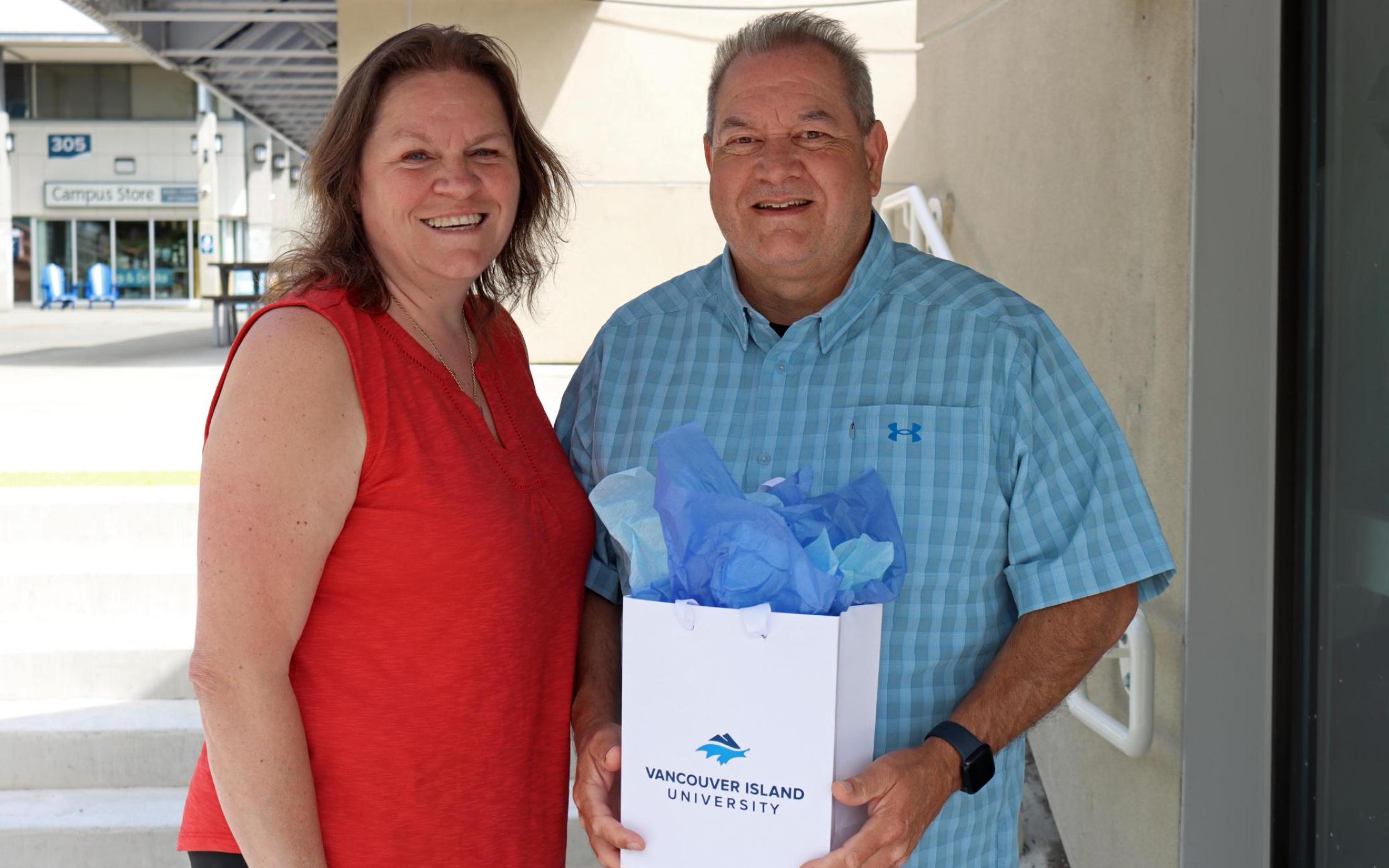 John with his wife Jen showing off the graduation gift he was given through the tuition waiver program