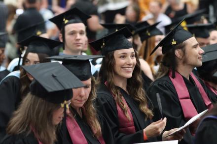A group of graduates smile and listen to speeches