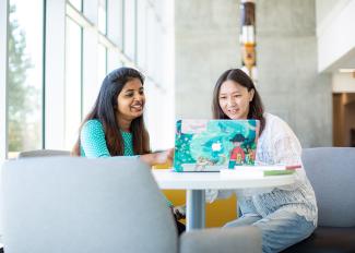 Two young women working on a laptop.