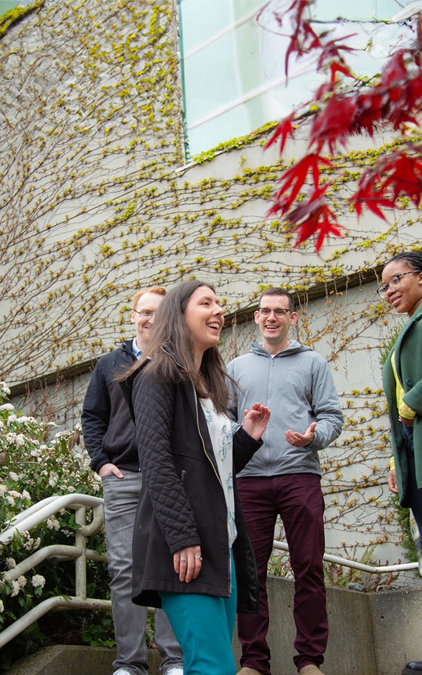 Students on a staircase near flowering shrubs and vines.